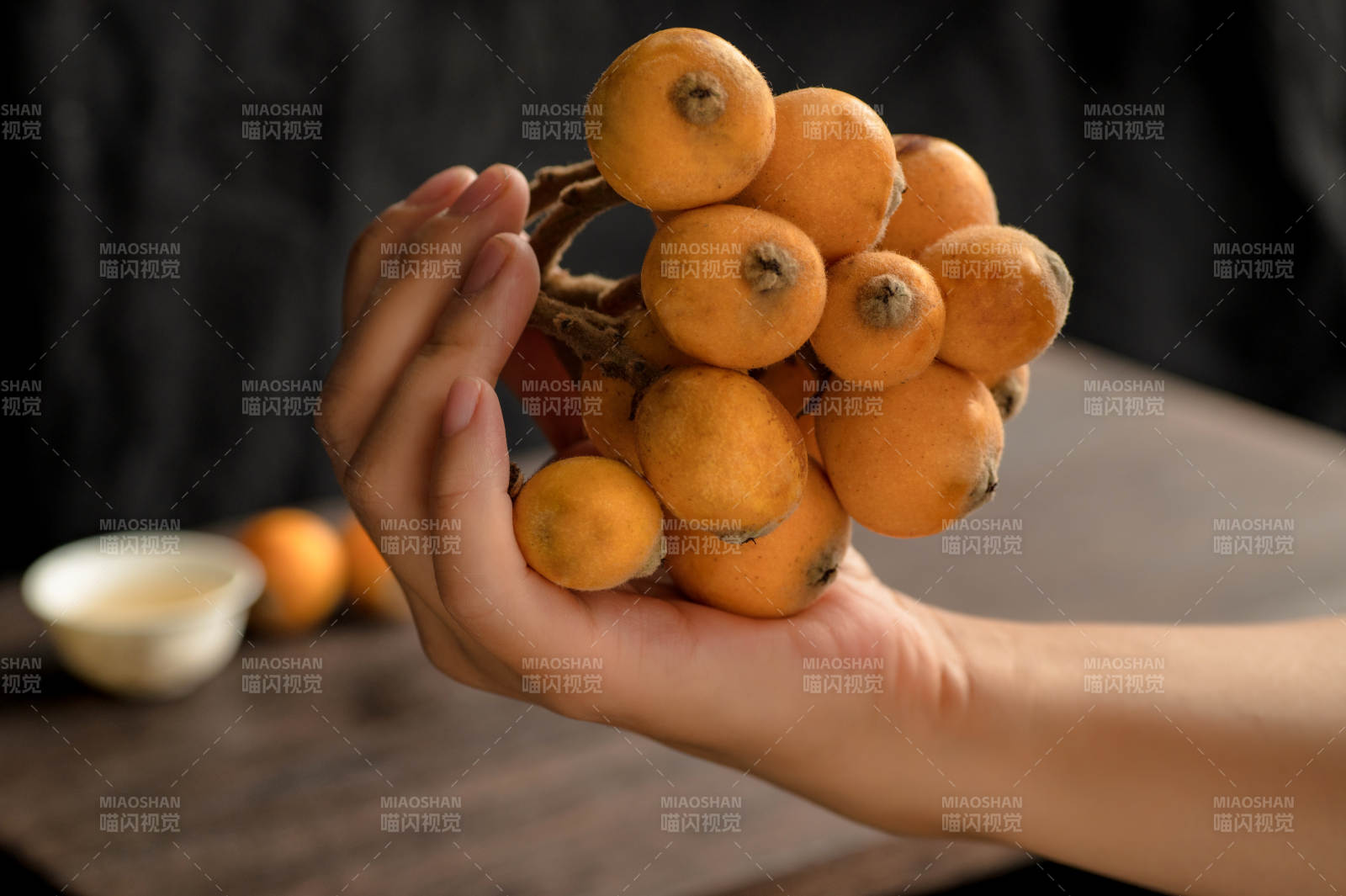 手持一串橙色枇杷