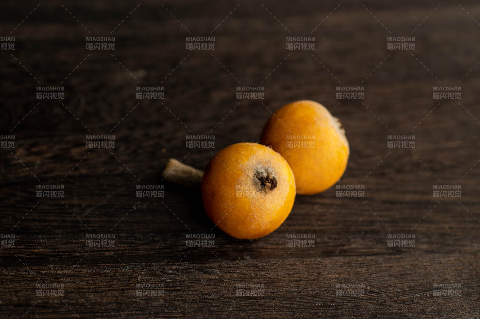 木桌上兩個橙色枇杷