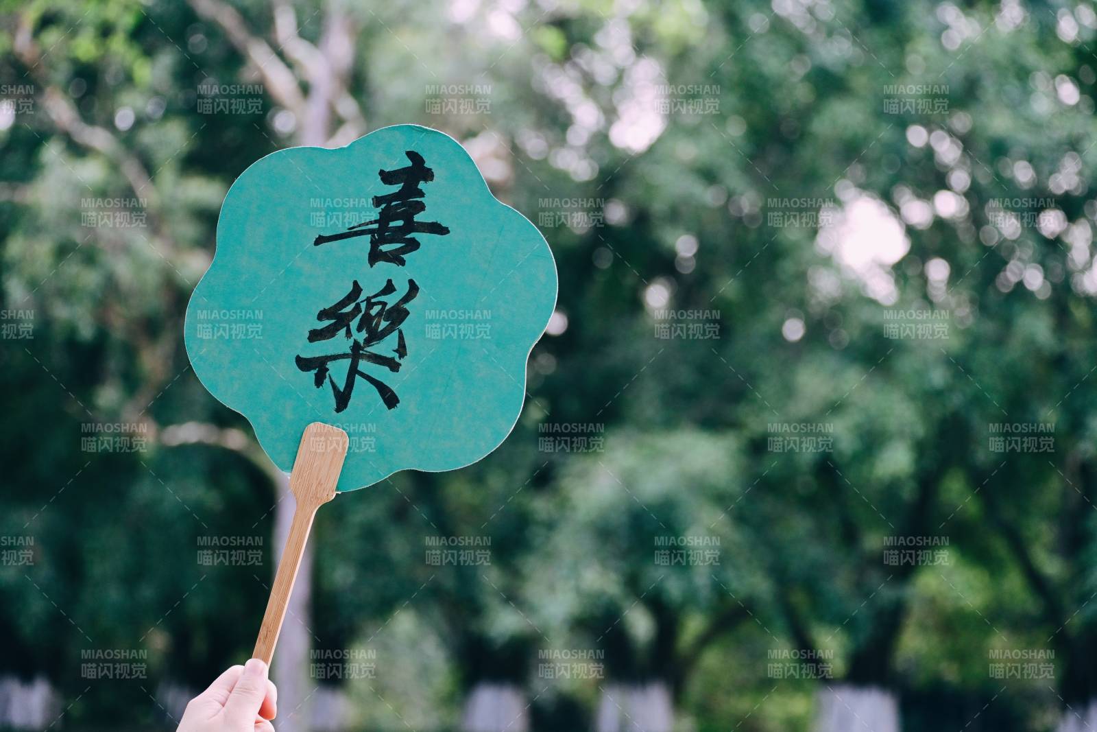 手持綠色扇子在樹下