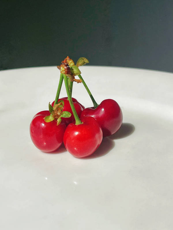 白色盤中四顆紅櫻桃開花