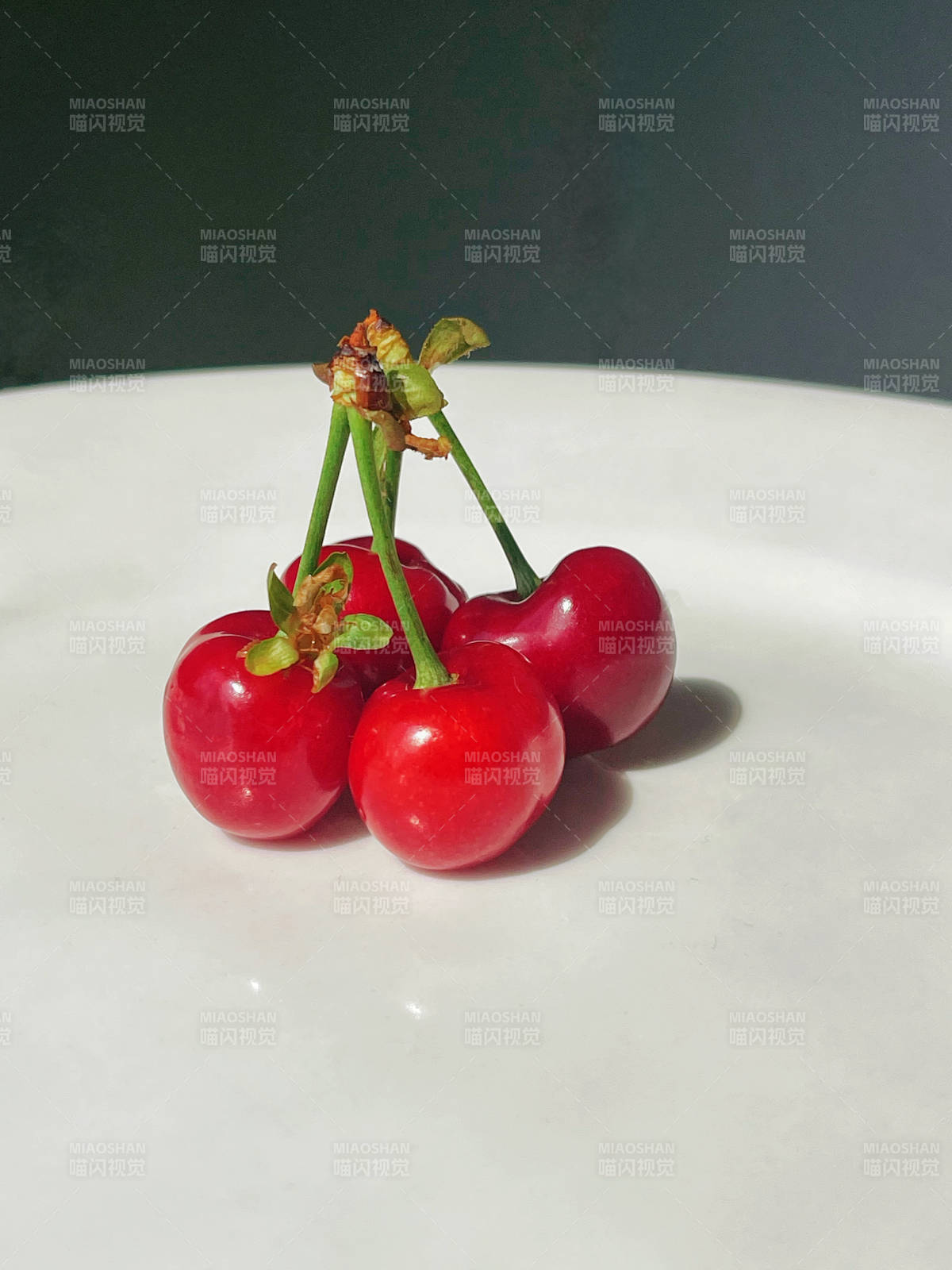 白色盤中四顆紅櫻桃開花