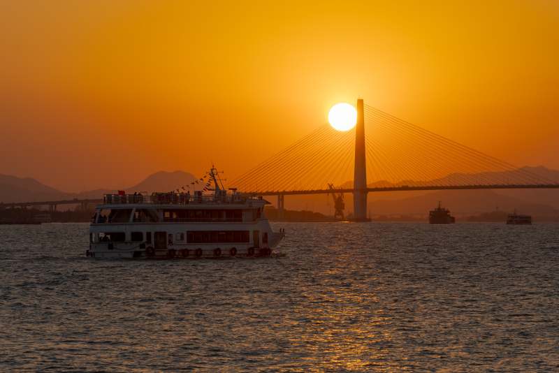 夕陽下的跨海大橋與游船