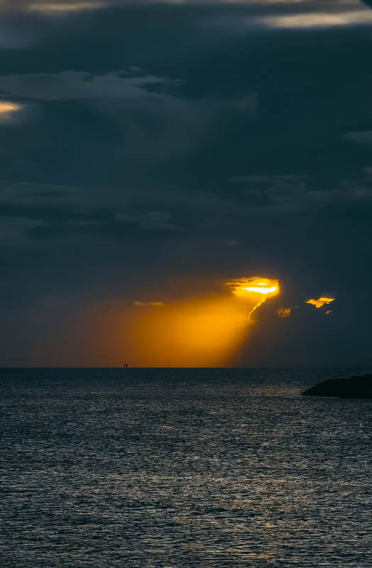 夕陽穿透云層照耀海面