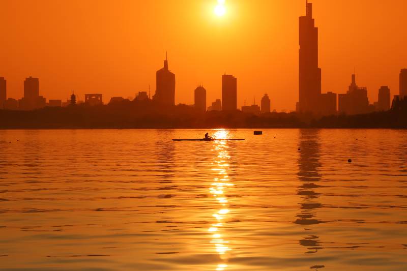 夕陽下的城市與劃船者