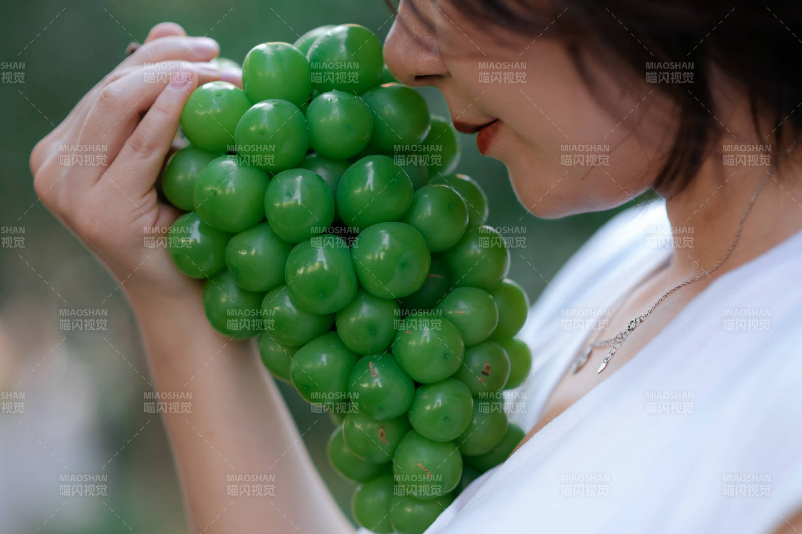 女子轻嗅绿色葡萄