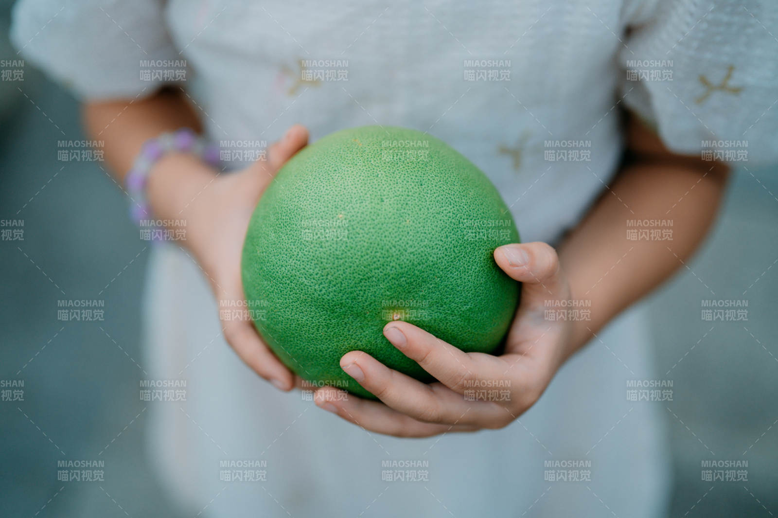 雙手捧著綠色柚子果
