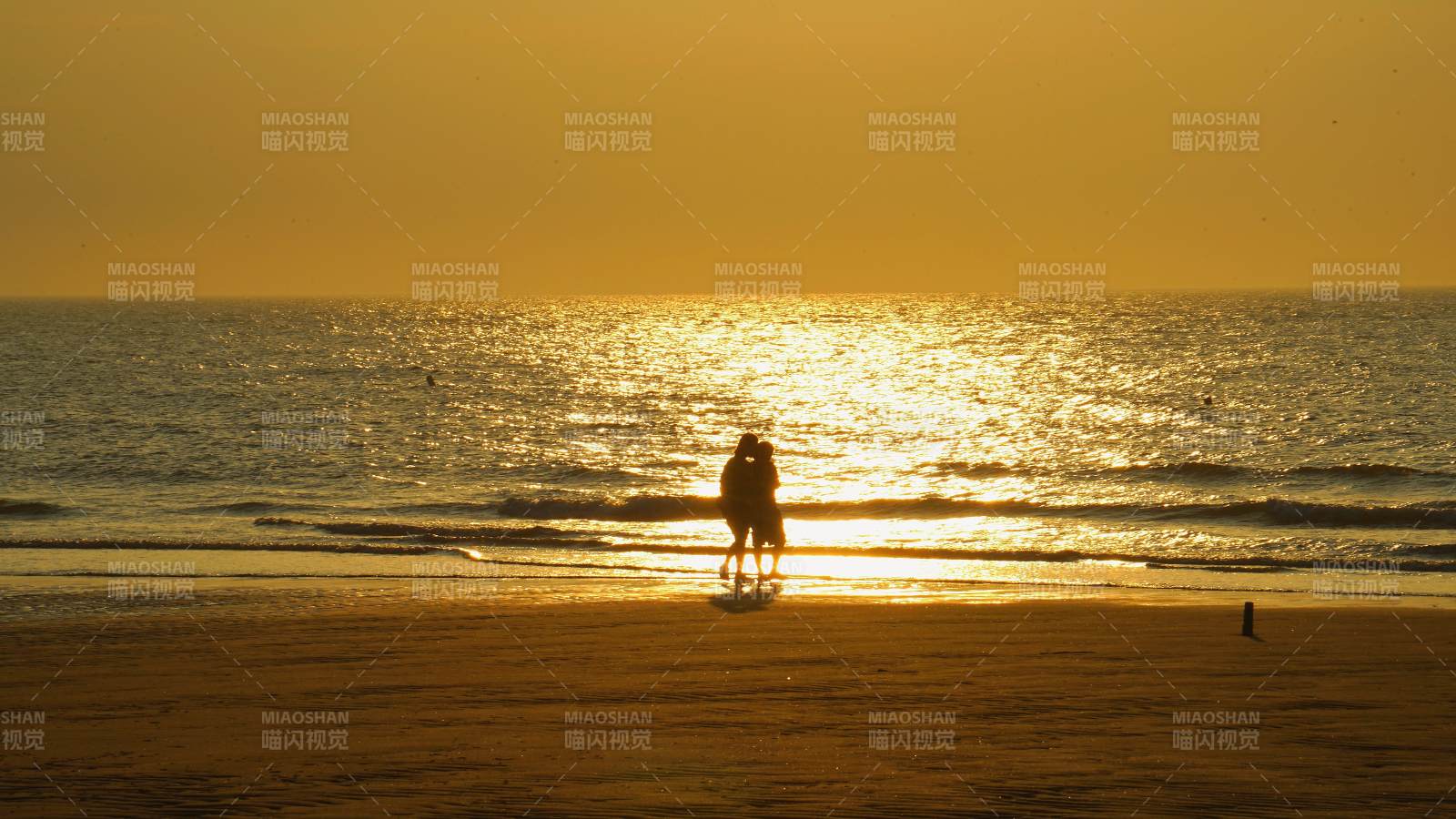 夕陽下的海灘情侶剪影
