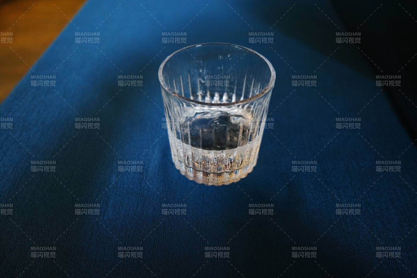 透明玻璃杯静置深蓝布上