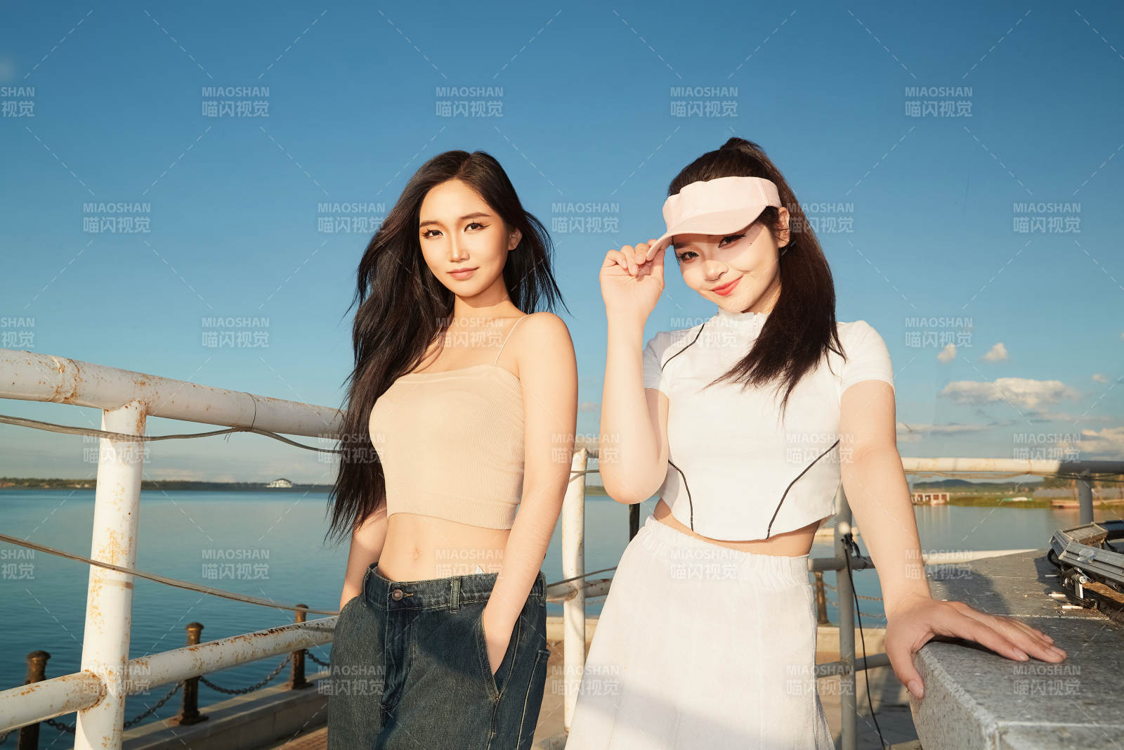 盛夏在景區湖邊燈塔上拍照游玩的美女們