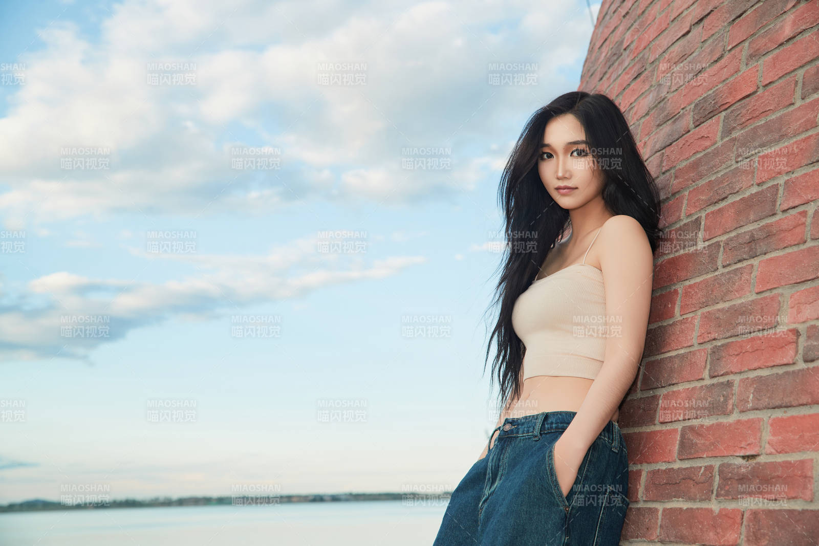 盛夏在景區湖邊燈塔上拍照游玩的美女