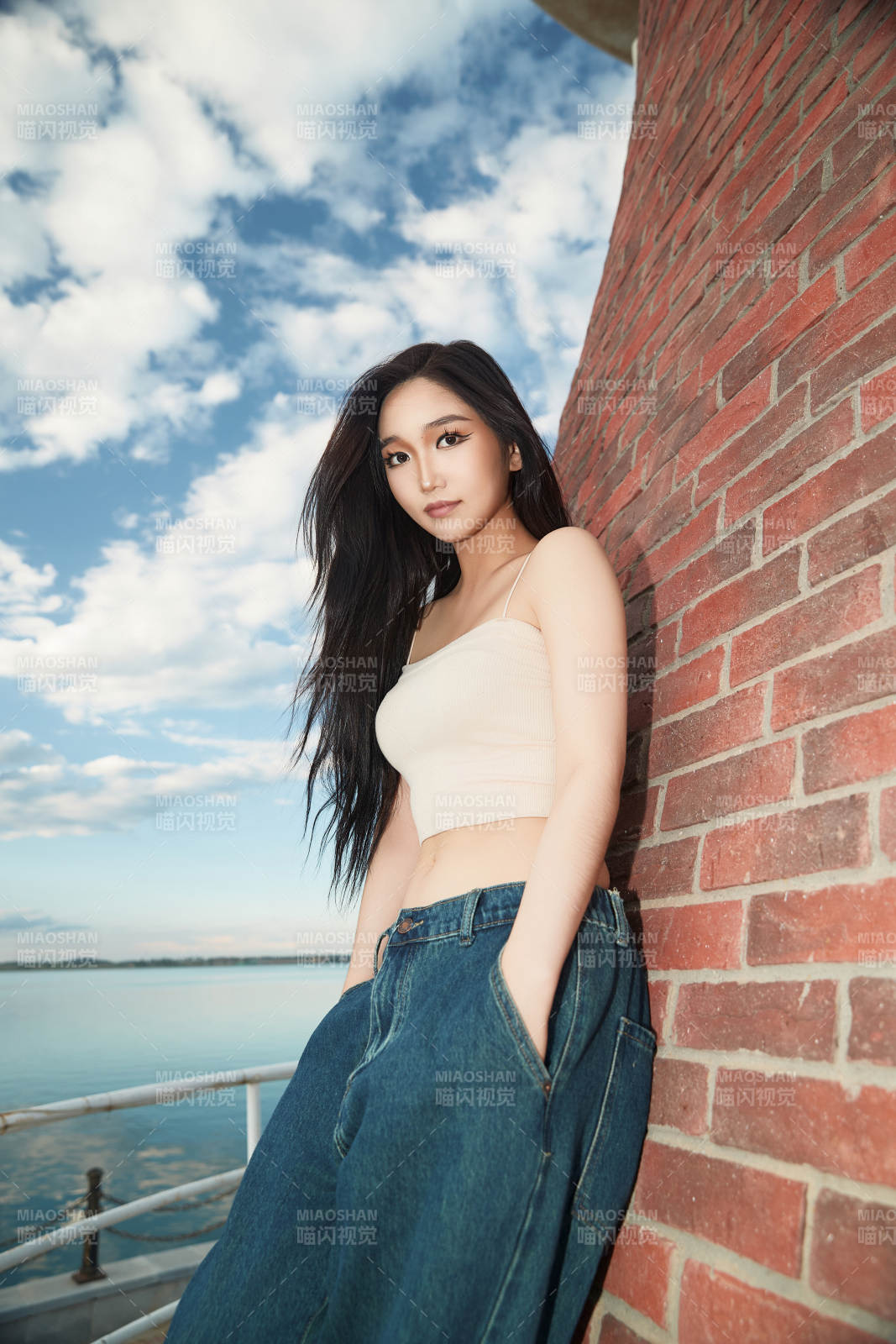 盛夏在景区湖边灯塔上拍照游玩的美女