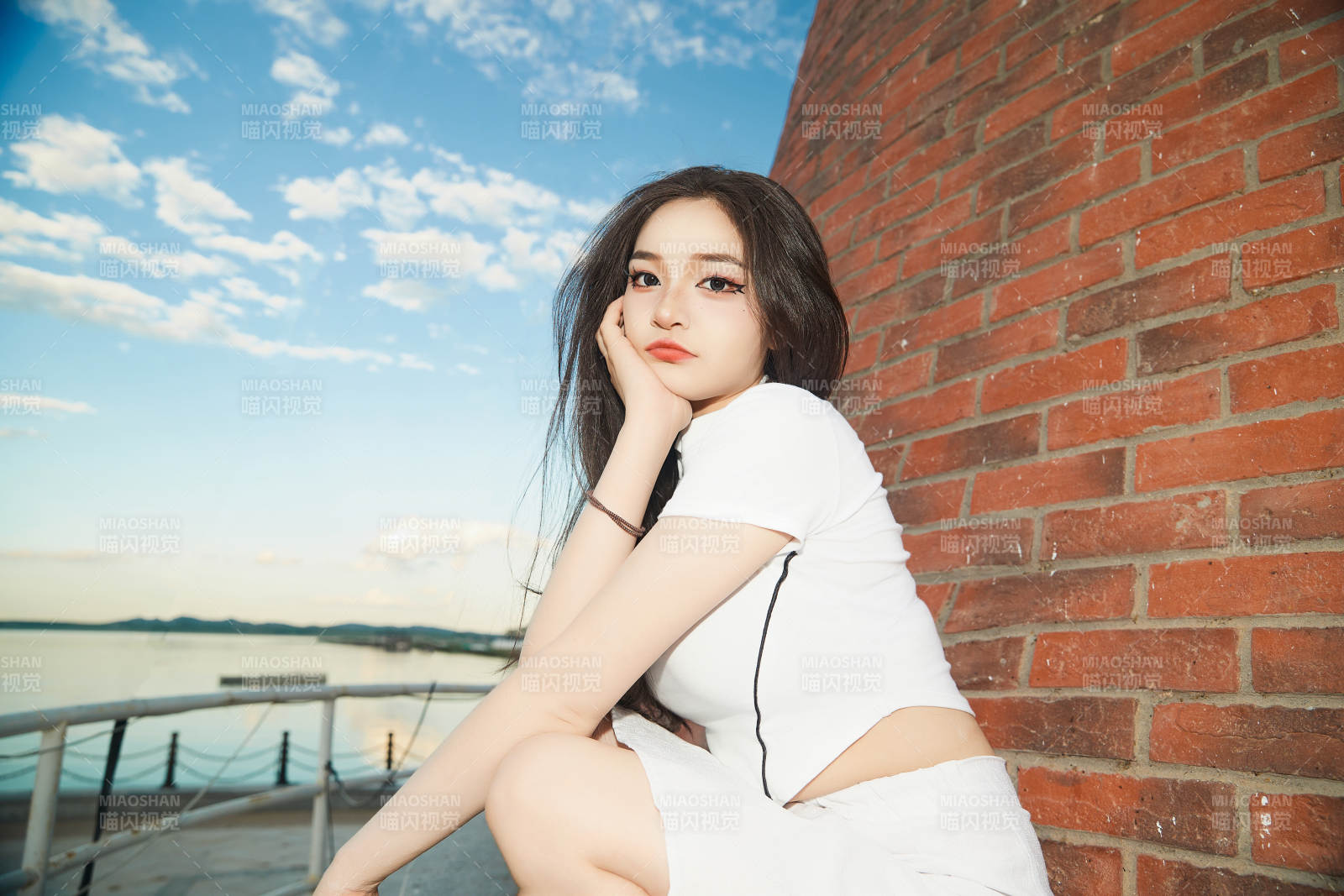 盛夏在景區湖邊燈塔上拍照游玩的美女