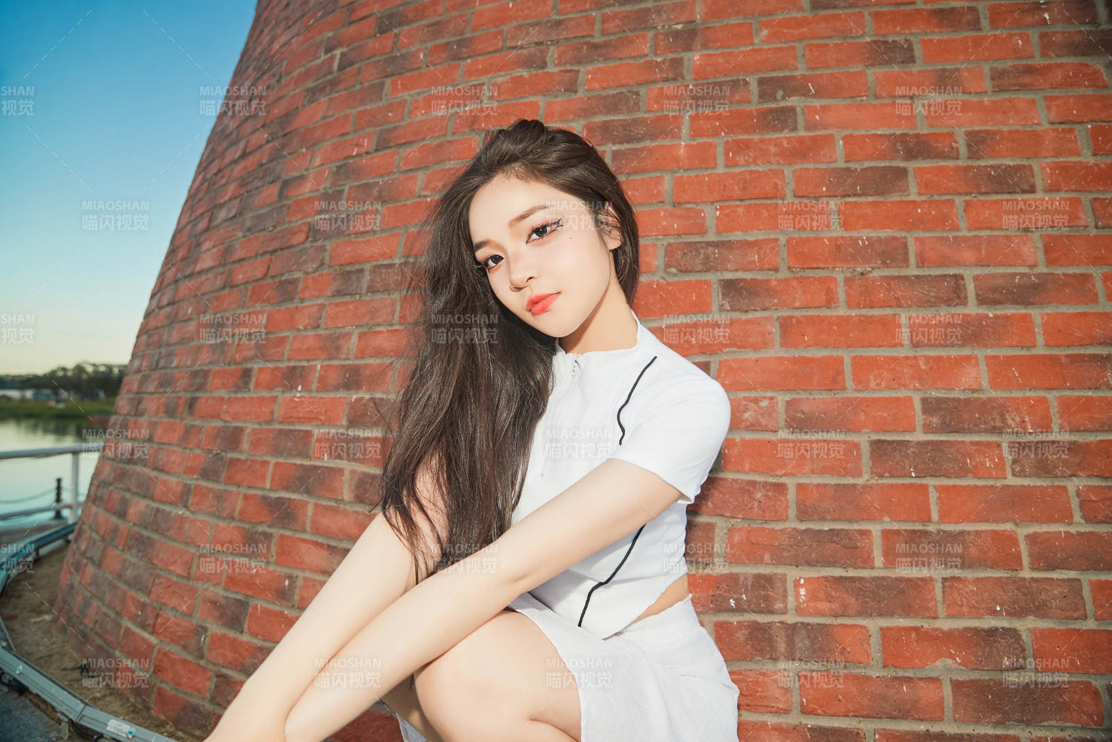 盛夏在景區湖邊燈塔上拍照游玩的美女