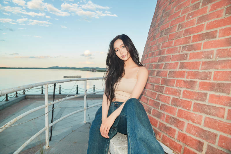 盛夏在景区湖边灯塔上拍照游玩的美女