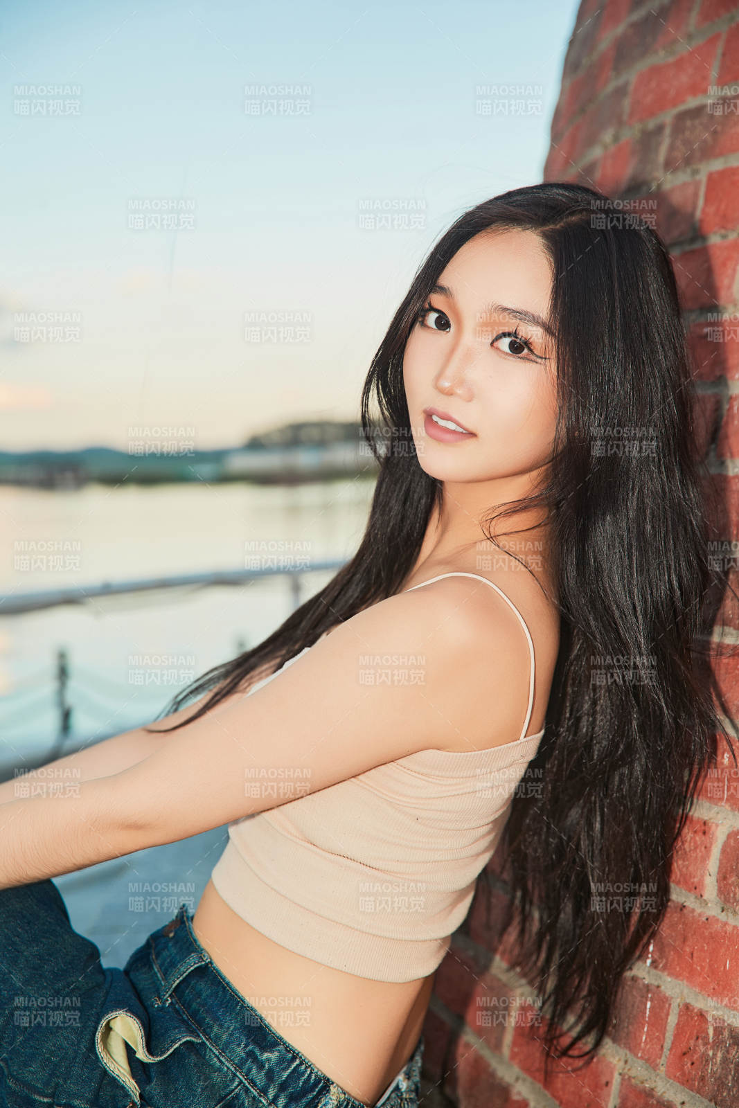 盛夏在景區(qū)湖邊燈塔上拍照游玩的美女