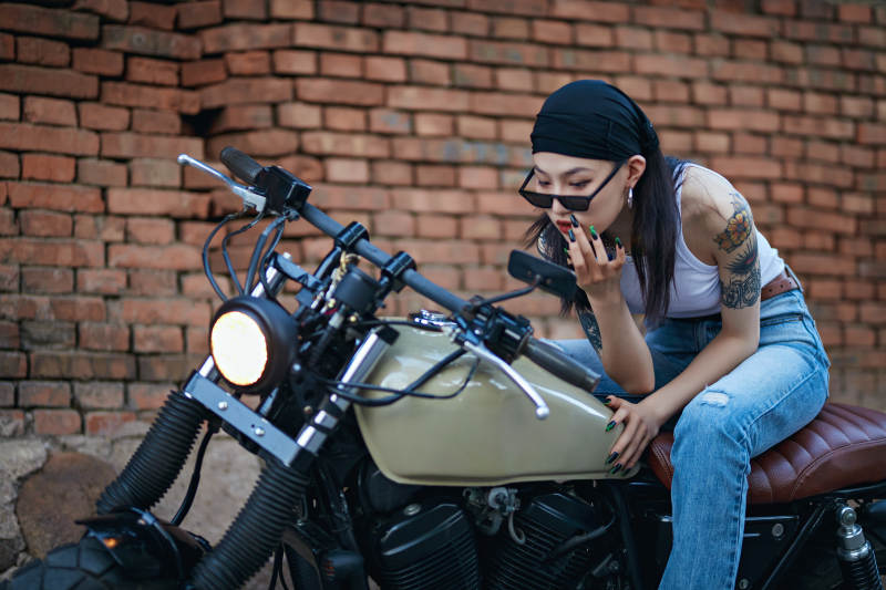 骑在复古摩托车上的时尚亚洲少女