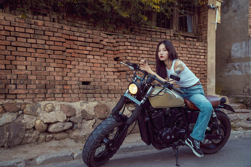骑在复古摩托车上的时尚亚洲少女