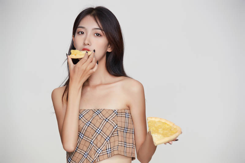 白色背景下吃着美味榴莲披萨的可爱少女