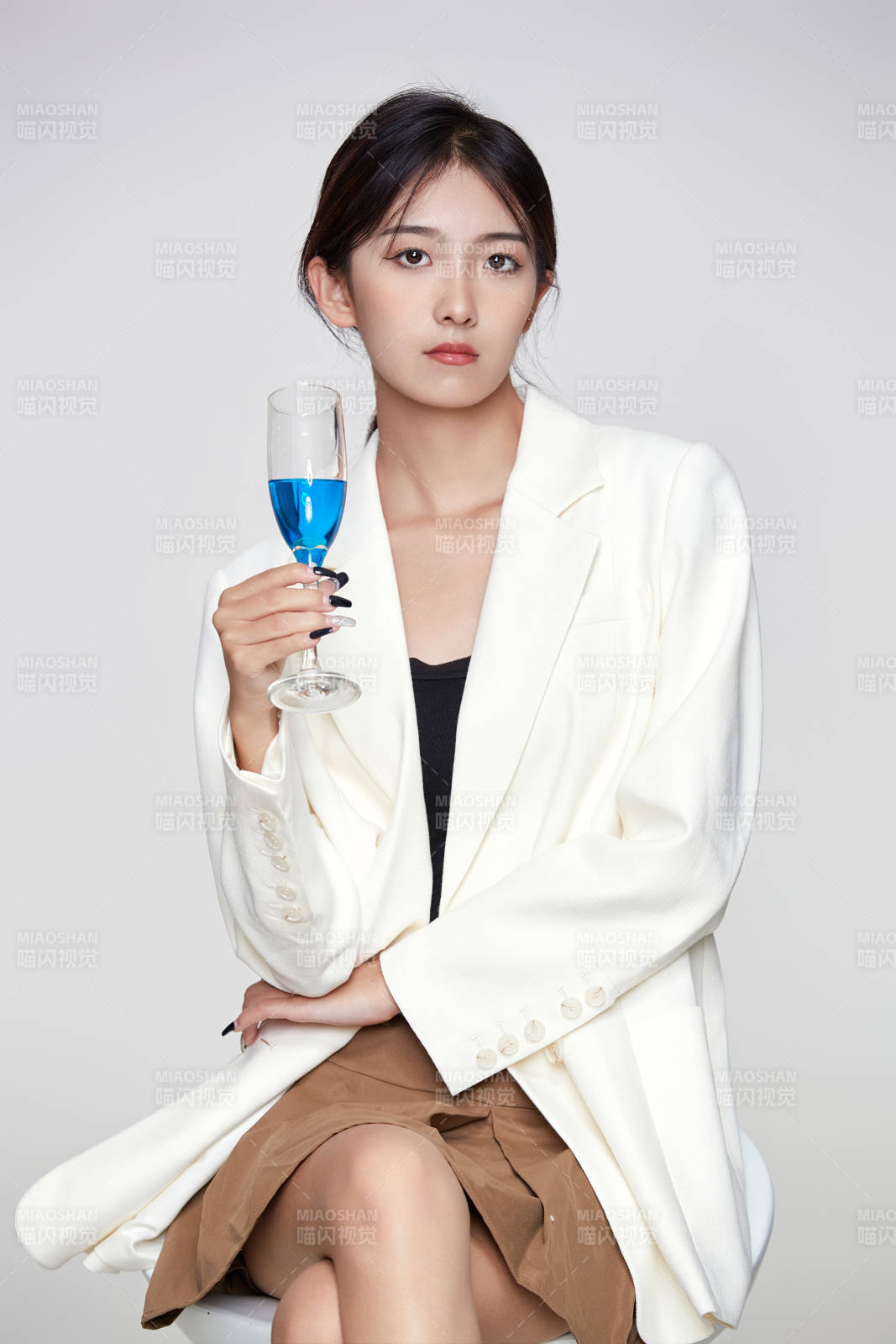 坐在椅子上手端酒杯的亞洲商務女性