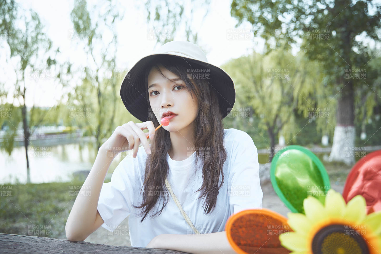 公園湖邊吃棒棒糖的亞洲可愛少女