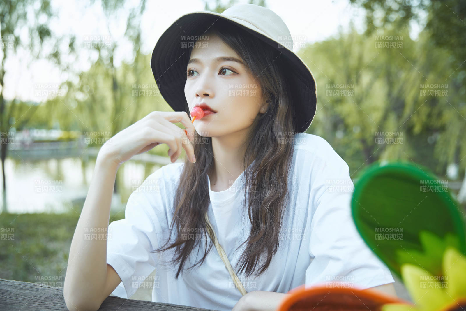 公園湖邊吃棒棒糖的亞洲可愛少女
