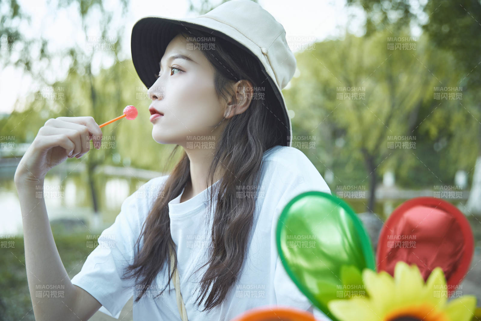 公园湖边吃棒棒糖的亚洲可爱少女