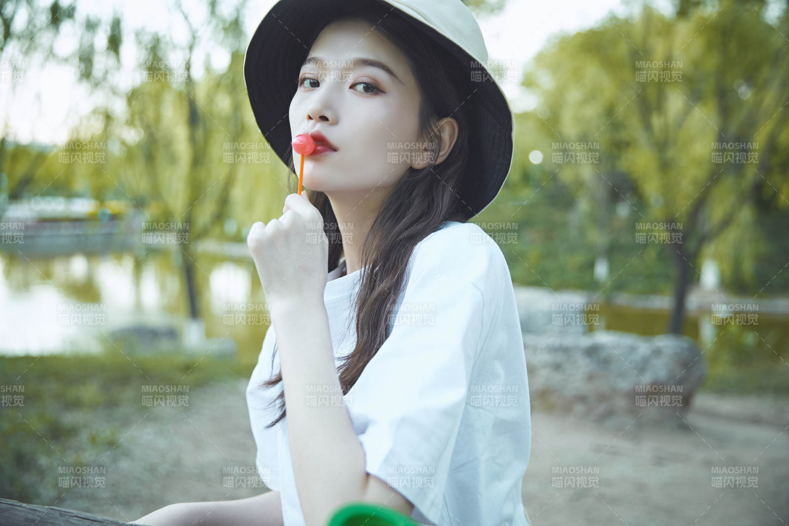 公園湖邊吃棒棒糖的亞洲可愛少女