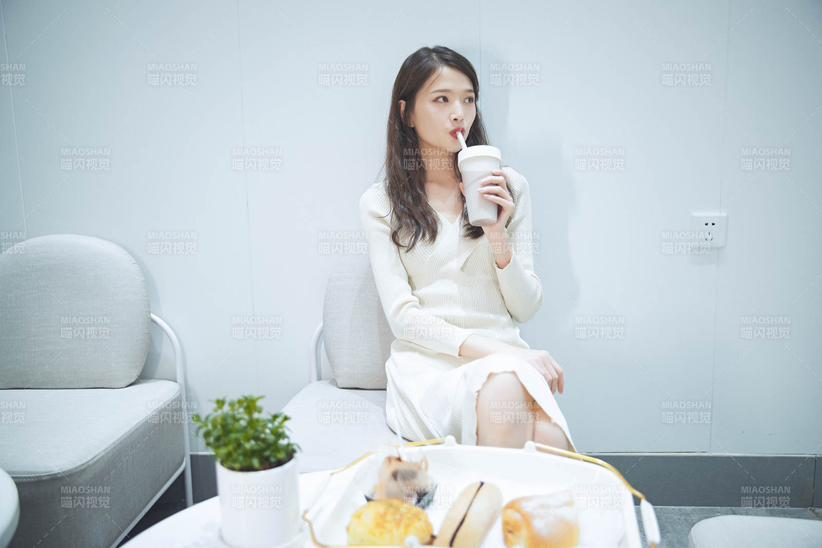 在烘焙店吃面包喝牛奶的可愛(ài)亞洲少女