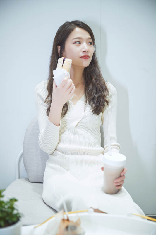 在烘焙店吃面包喝牛奶的可爱亚洲少女