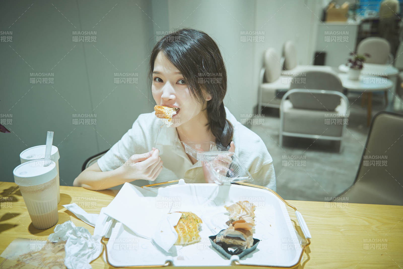 在烘焙店吃面包喝牛奶的可愛(ài)亞洲少女