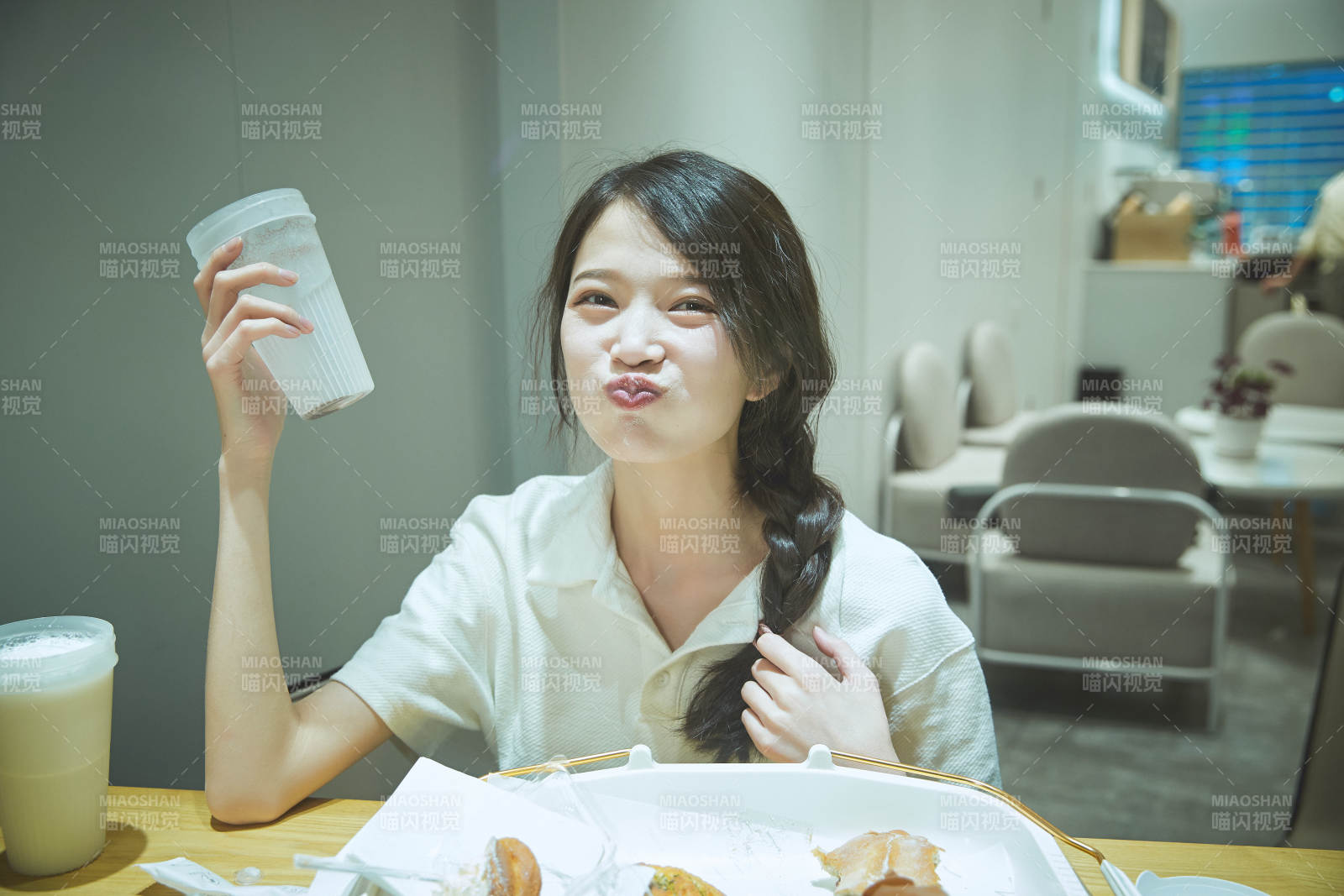 在烘焙店吃面包喝牛奶的可愛亞洲少女