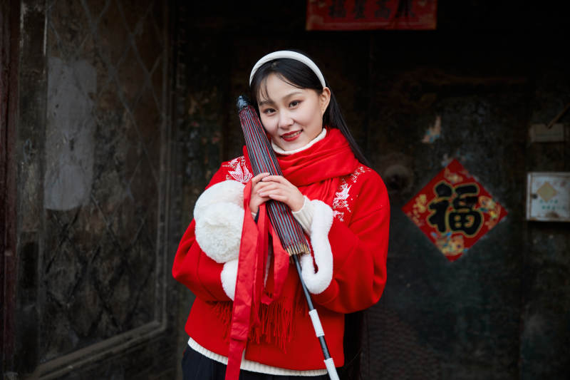 雪后在老城古巷穿着喜庆服饰的亚洲少女