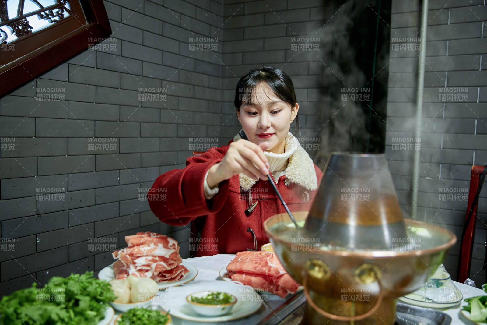 在饭店吃传统铜锅涮肉的亚洲少女