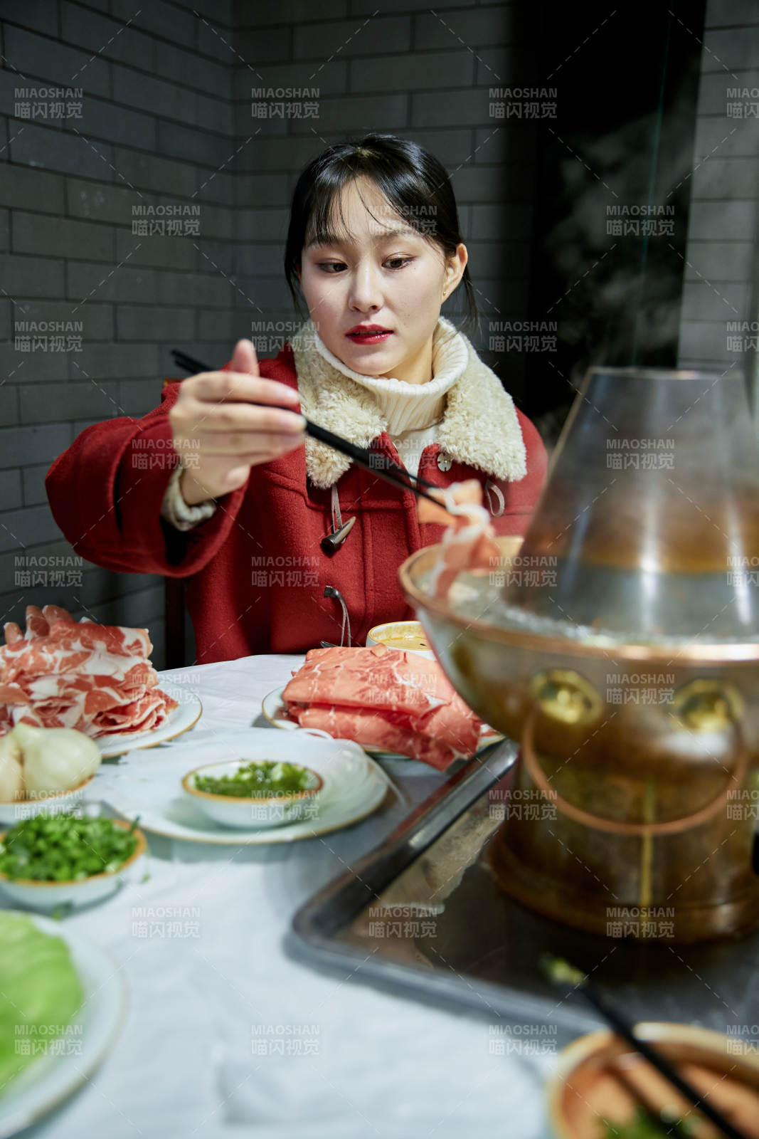 在饭店吃传统铜锅涮肉的亚洲少女
