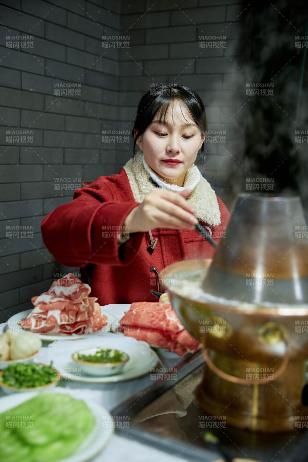 在飯店吃傳統(tǒng)銅鍋涮肉的亞洲少女