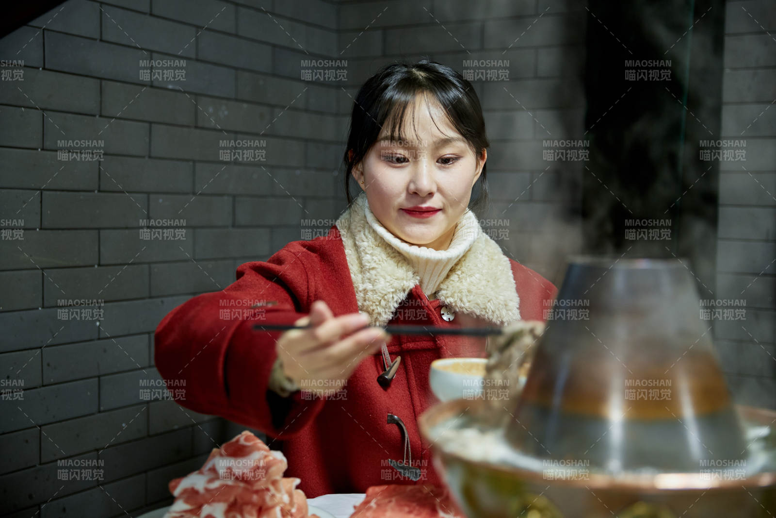 在饭店吃传统铜锅涮肉的亚洲少女