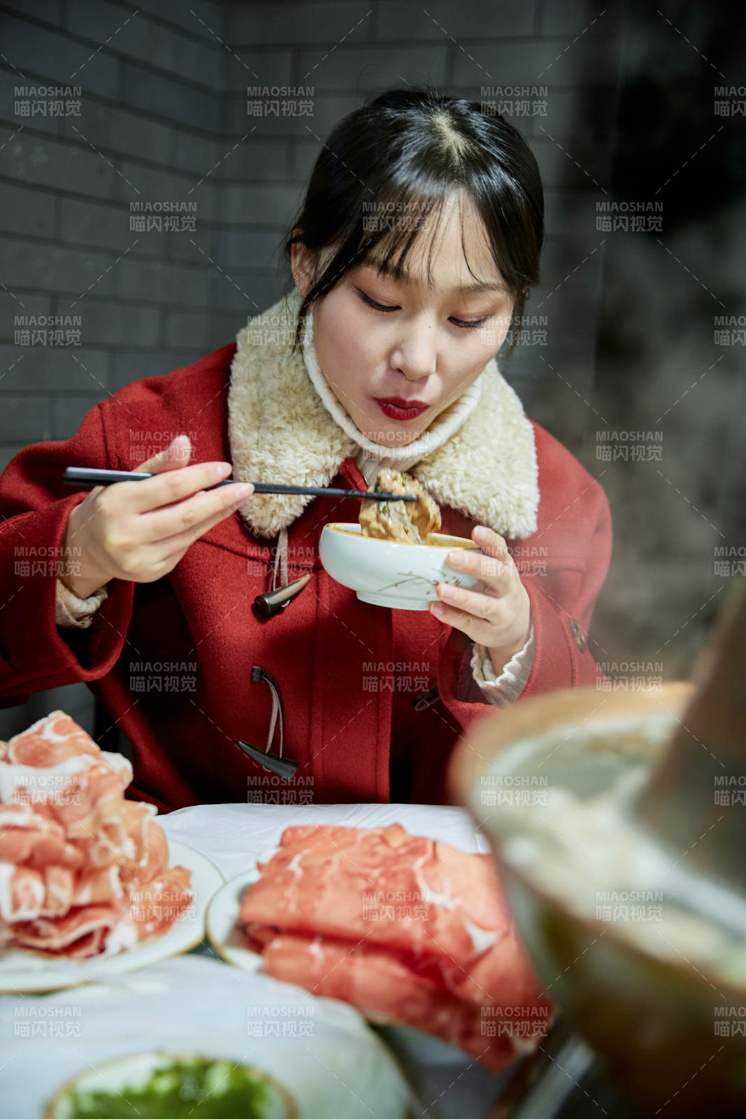 在飯店吃傳統銅鍋涮肉的亞洲少女