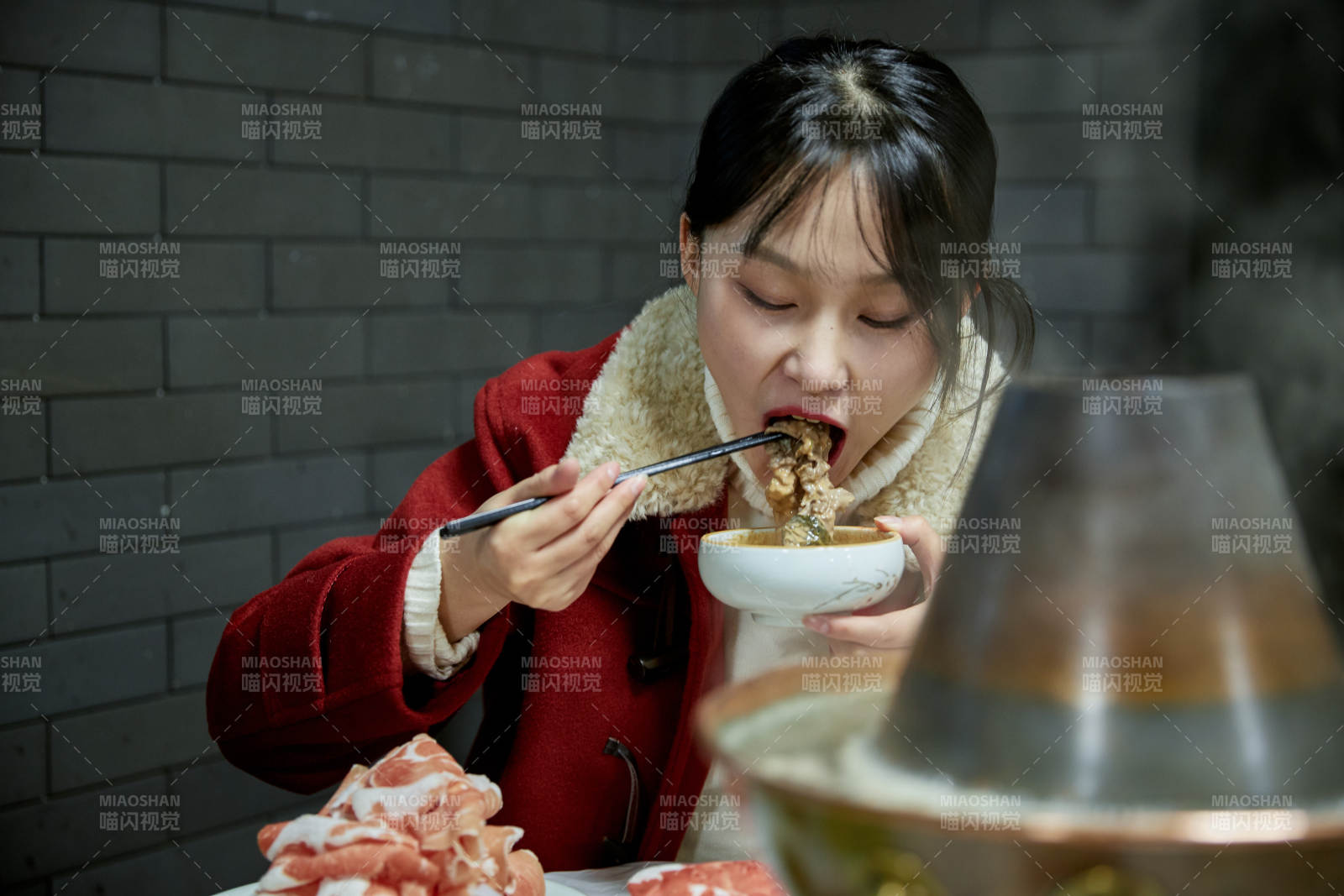 在飯店吃傳統銅鍋涮肉的亞洲少女