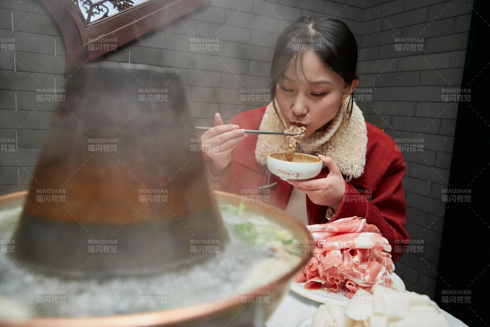 在飯店吃傳統(tǒng)銅鍋涮肉的亞洲少女