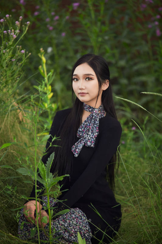 盛夏夕阳照射下花丛草地中的亚洲美女