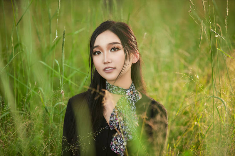 盛夏夕阳照射下花丛草地中的亚洲美女