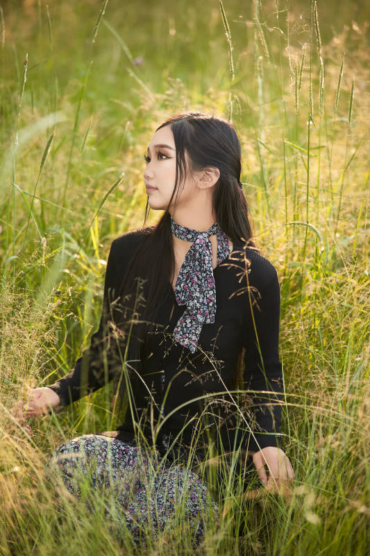 盛夏夕阳照射下花丛草地中的亚洲美女