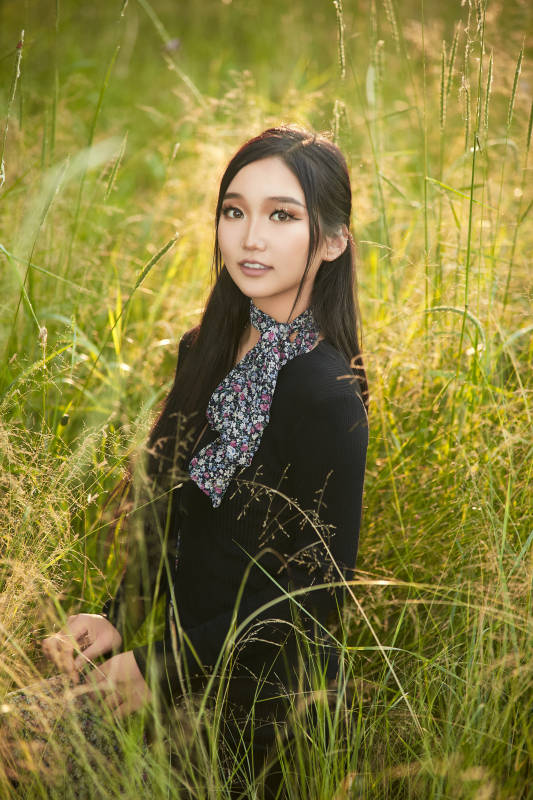 盛夏夕阳照射下花丛草地中的亚洲美女