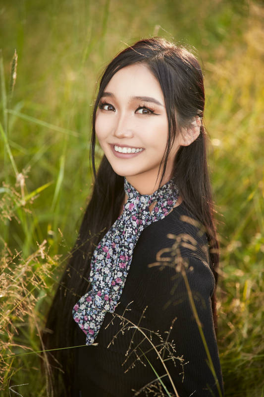 盛夏夕阳照射下花丛草地中的亚洲美女