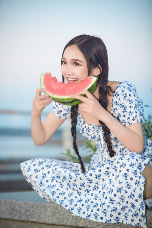 夏天在公园湖边开心吃西瓜的美女