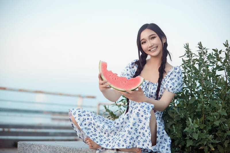 夏天在公园湖边开心吃西瓜的美女