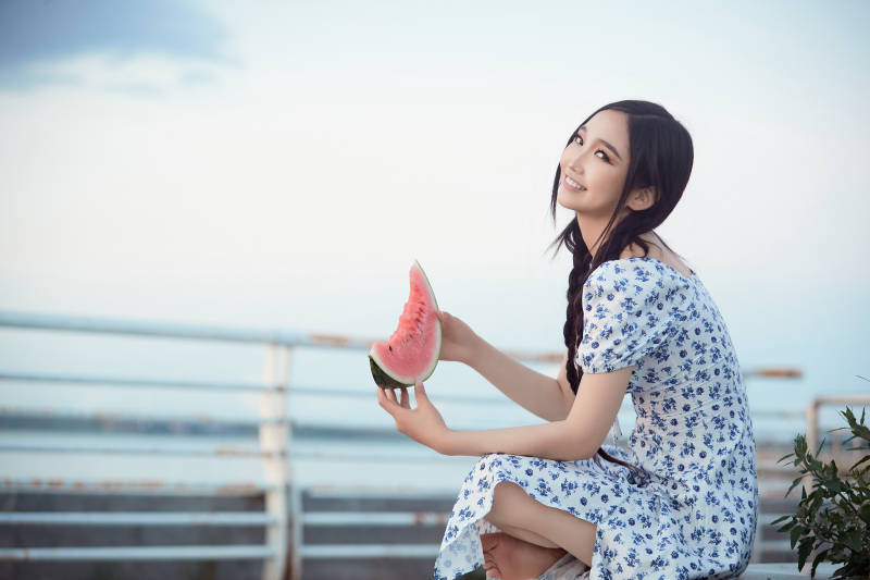 夏天在公园湖边开心吃西瓜的美女