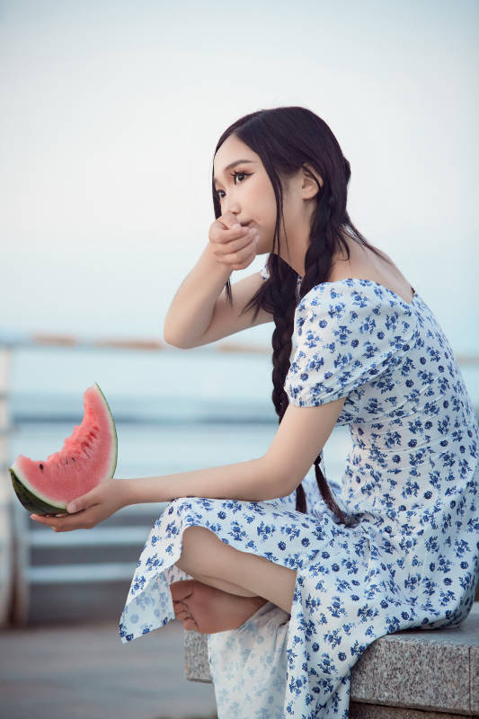 夏天在公园湖边开心吃西瓜的美女