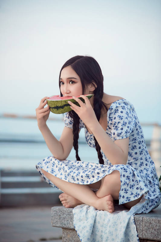 夏天在公园湖边开心吃西瓜的美女