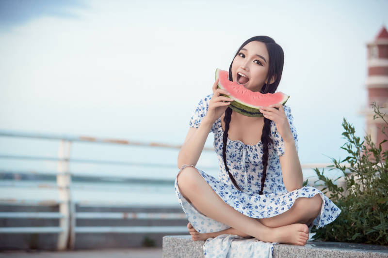 夏天在公园湖边开心吃西瓜的美女